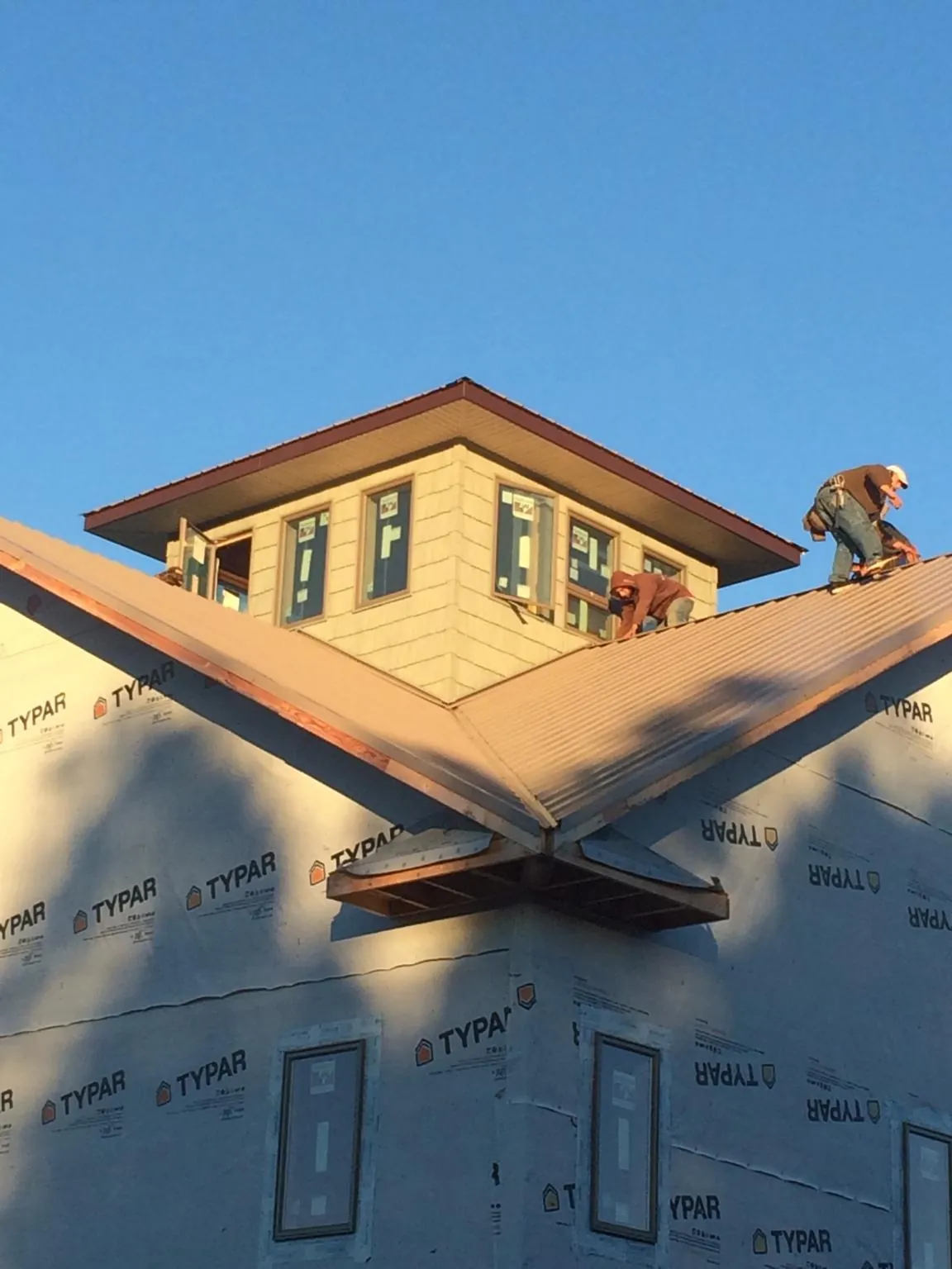 Roofers working around a rooftop cupola on a new metal roof at sunset — Roof Waterproofing in Martin by Roofing Brothers
